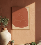 Framed abstract artwork on a warm-toned wall with decorative plants.